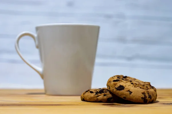 Group of Chocolate chips cookies with a coffee cup on a wooden table, white empty background