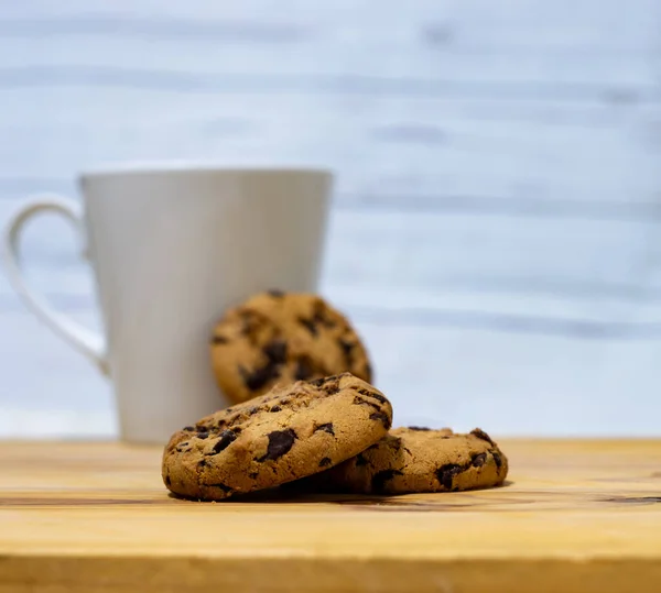 Group of three Chocolate chips cookies with a coffee cup on a wooden table, white empty background