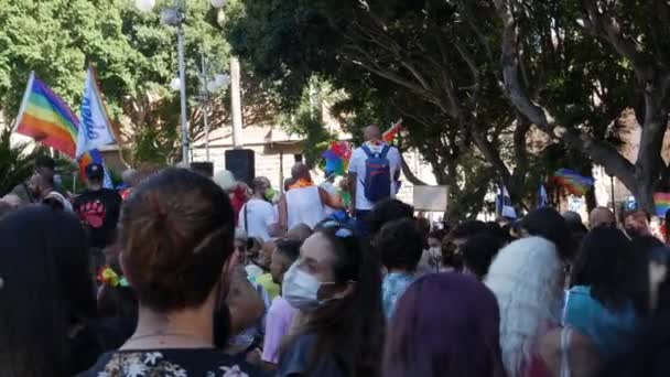 Толпа машет радужными флагами в медицинских масках — стоковое видео