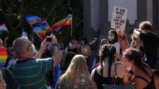 Menina segurando um sinal se Deus odeia gays por que somos tão quentes enquanto um homem tira uma foto — Vídeo de Stock