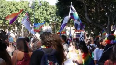 Koronavirüsü önlemek için tıbbi maske takan büyük bir kalabalık lgbt gökkuşağı bayrakları sallıyor.