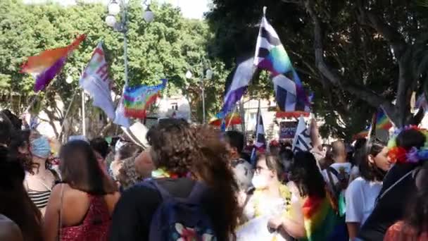 Koronavirüsü önlemek için tıbbi maske takan büyük bir kalabalık lgbt gökkuşağı bayrakları sallıyor. — Stok video