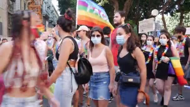 Толпа наступает в городе марш размахивая радужными флагами и носить красочные цветочные ожерелья для lgbt права — стоковое видео