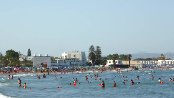 Πολλοί άνθρωποι παίζουν δίπλα στη θάλασσα σε μια παραλία της πόλης σε μια ζεστή καλοκαιρινή μέρα — Αρχείο Βίντεο