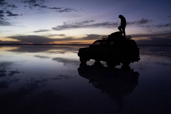 İnsanlar Salar de Uyuni, Bolivya 'da günbatımının tadını çıkarıyorlar.
