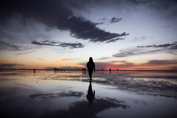 İnsanlar Salar de Uyuni, Bolivya 'da günbatımının tadını çıkarıyorlar.