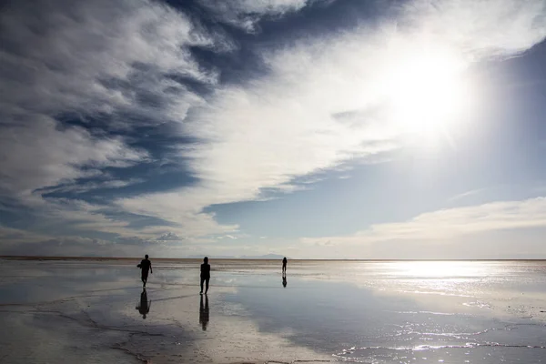 İnsanlar Salar de Uyuni, Bolivya 'da günbatımının tadını çıkarıyorlar.