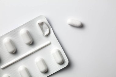 Bir tanesi izole edilmiş beyaz yüzeye basılı olan açılı su toplayıcı haplar. Kullanılan ilaç hapları basit.