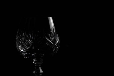 Dramatik ışıklandırmada siyah arka planda boş kristal brendi bardağı. İzole edilmiş iyi yemek, cam bar ve restoran.