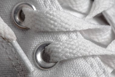 Kumaştan yapılmış beyaz spor ayakkabı bağcığının yakınına. Ayak takımı giysi reklamı