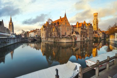 Bruges, Belçika 'nın Bruges şehrinde gün batımında eski binalarla gökyüzü çiziyor..
