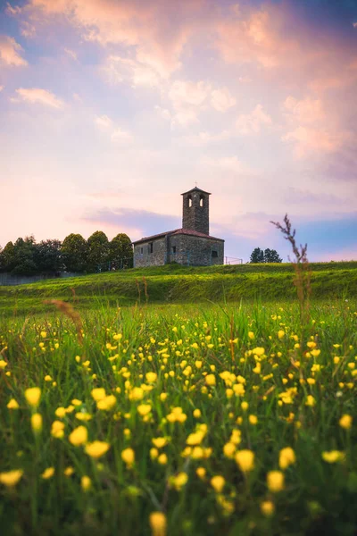 前景に花のフィールドと背景に古い教会と風景。Garbagnate Monastero,レッコ,イタリア. — ストック写真