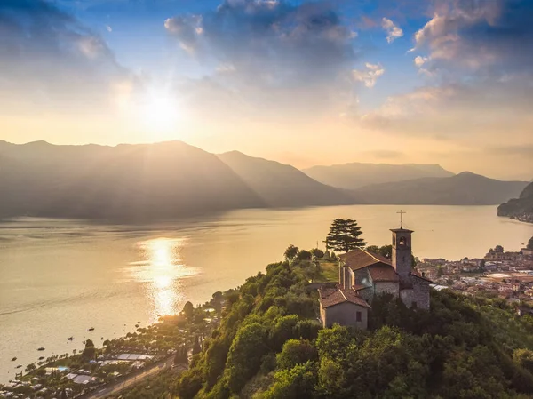 Vista panorâmica aérea bonita do drone ao lago de Iseo com a igreja no alto da colina, Lombardia, Itália — Fotografia de Stock