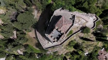 İnsansız hava aracı görüntüleri, selvi ağaçlarıyla çevrili kayalık bir tepedeki tarihi saat kulesine doğru uçuyor. Sonra Brisighella, Emilia-Romagna, İtalya 'nın en üst manzarası için aşağıya iniyor..