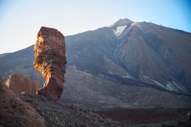 Ön planda kaya oluşumu ve arka planda volkanik dağ manzarası, lav ve erozyon tarafından şekillendirilen kurak arazi, açık gökyüzü ve gün ışığı, Tenerife adası, Kanarya Adaları, İspanya.