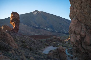 Ön planda kaya oluşumu ve arka planda volkanik dağ manzarası, lav ve erozyon tarafından şekillendirilen kurak arazi, açık gökyüzü ve gün ışığı, Tenerife adası, Kanarya Adaları, İspanya.