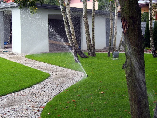 Садовая автоматическая система орошения, работающий дождеватель — стоковое фото