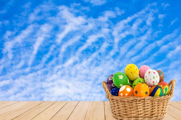 Colorful Easter eggs in a basket on wood texture on blue sky bac Stock Photo