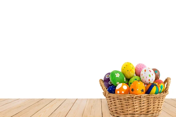 Colorful Easter eggs in a basket on wood texture isolated on whi Royalty Free Stock Images