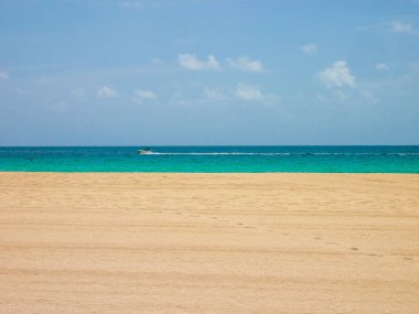 Miami sahillerinde gökyüzü, deniz ve kum manzarası. Yaz mevsiminde bir sürat teknesi geçerken..