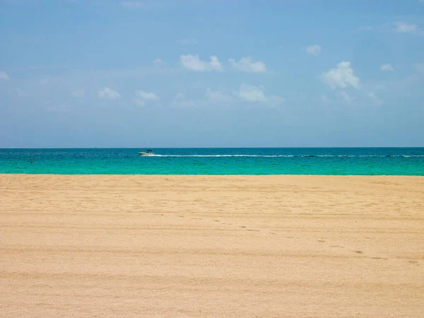 Miami sahillerinde gökyüzü, deniz ve kum manzarası. Yaz mevsiminde bir sürat teknesi geçerken..
