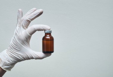 Hemşirenin eldiven taktığı eldiven fotokopi alanındaki ilaç ampulünü gösteriyor..