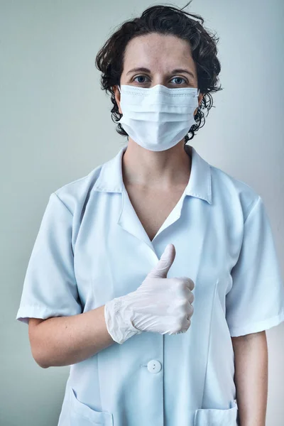 nurse wearing mask and gloves making thumbs up.