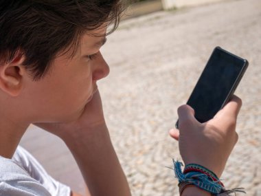 Akıllı telefonunu kullanan sıkılmış çocuğun fotoğrafı..