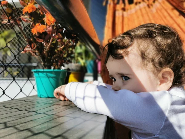 Küçük bebek yazın balkonda güvenlik ağının arkasında.