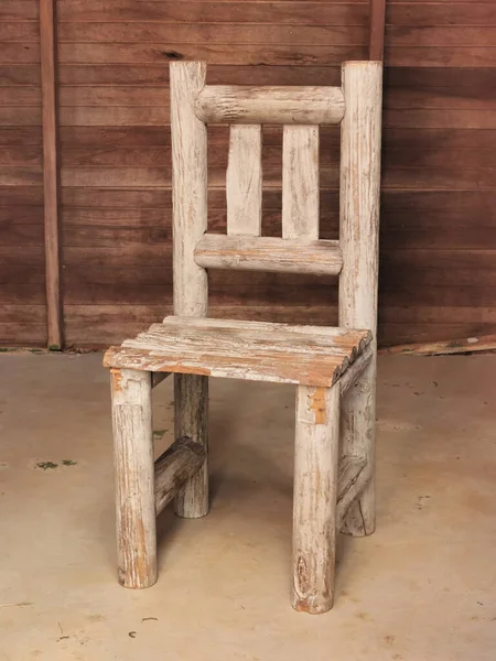 Tiny wooden chair with a wooden background .