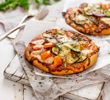 Bir ahşap tahta üzerinde sebze eklenmesi ile küçük ev yapımı pizza