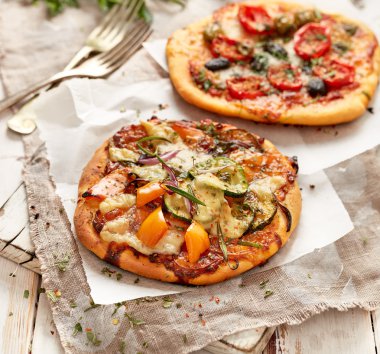 Bir ahşap tahta üzerinde sebze eklenmesi ile küçük ev yapımı pizza