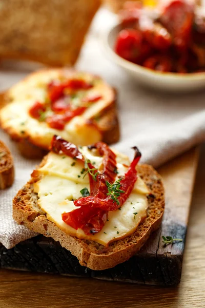 Toasts with smoked sheep milk cheese, sun-dried tomatoes and herbs — Stock Photo, Image