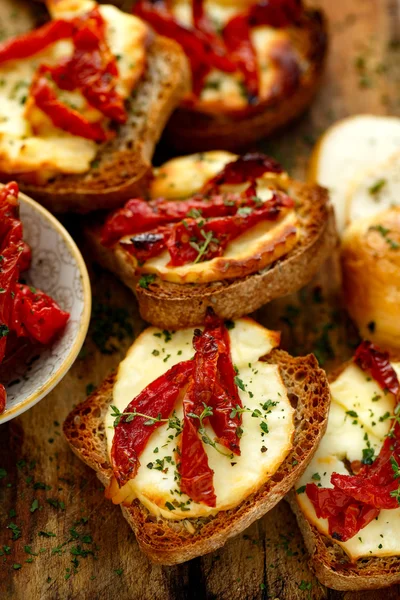 Toasts with smoked sheep milk cheese, sun-dried tomatoes and herbs — Stock Photo, Image