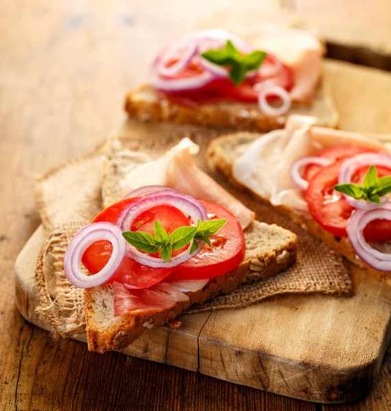 Sandwich met gerookte ham, tomaat, rode ui en verse oregano — Stockfoto