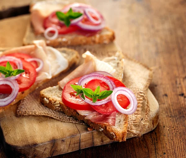 Бутерброд з копченою шинкою, помідорами, червоною цибулею та свіжим орегано — стокове фото