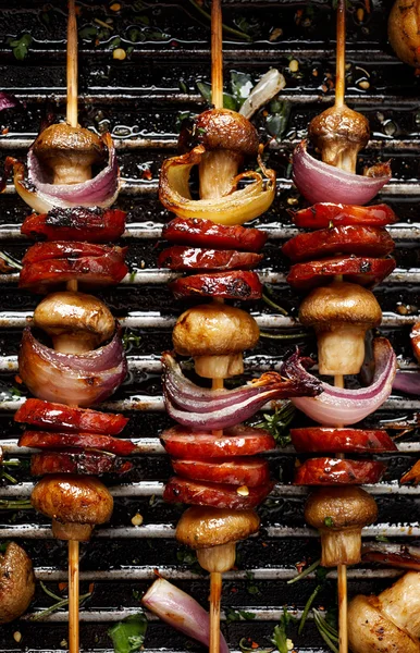 Espetos grelhados de linguiça, cogumelos e cebola em uma panela de grelha — Fotografia de Stock
