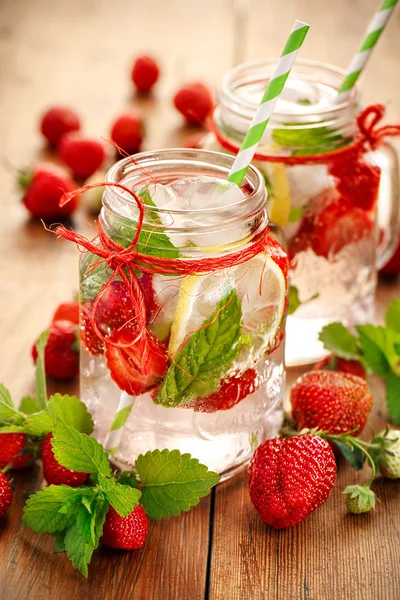 Agua con sabor a fresas frescas, limón y menta en frascos de vidrio — Foto de Stock