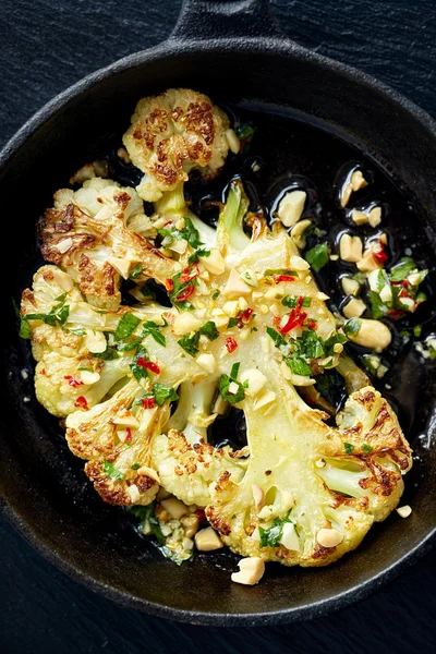 Roasted cauliflower steak with the addition dip with peanuts, chili and fresh parsley on iron frying pan — Stock Photo, Image