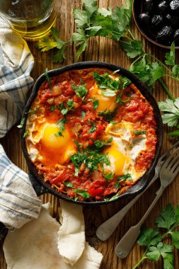 Geleneksel Shakshuka tabağı ahşap masa üzerinde dökme demir bir tavada servis edilir.