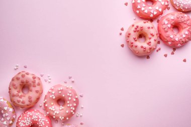 Arkaplanda pembe jöleli donutlar ve metin için çeşitli serpiştirmeler var. Sevgililer Günü veya doğum günü geçmişi