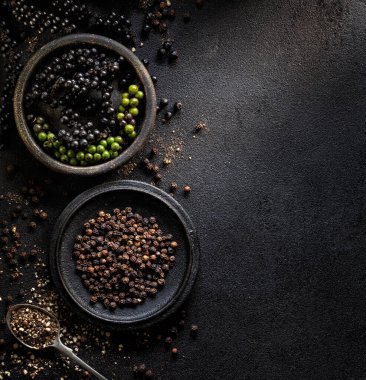 Siyah taş masadaki kaselerde siyah biber manzarası.