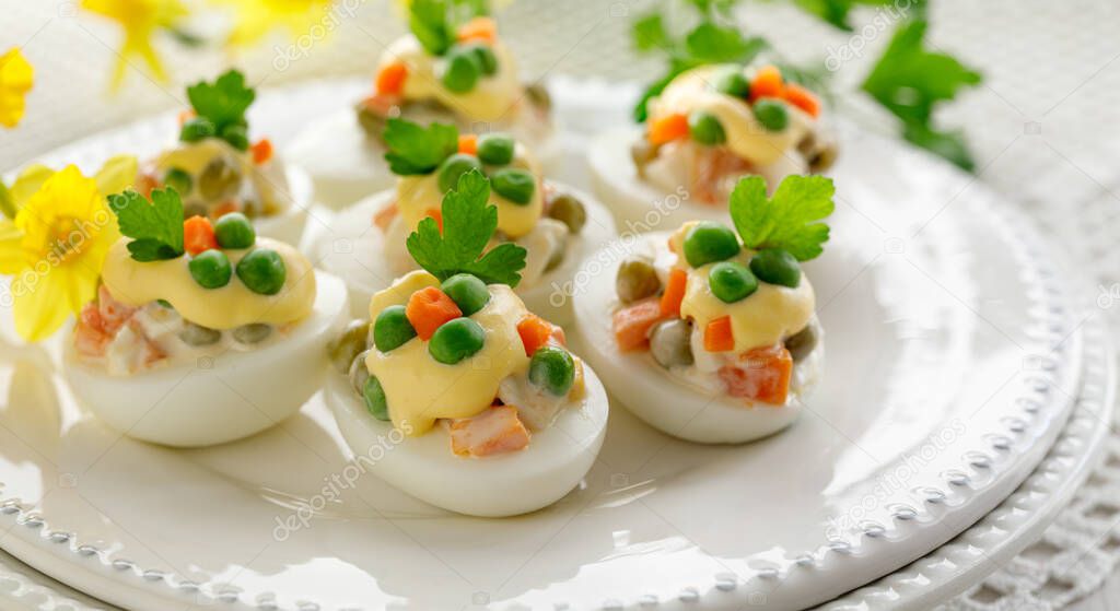 Easter boiled eggs stuffed with vegetable salad with mayonnaise served on a white plate close up view