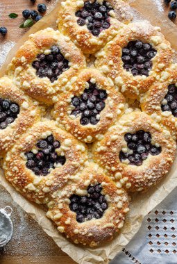 Geleneksel tatlı maya çörekleri, yanında yabanmersini ve tereyağlı çörekler, üst manzara. Lezzetli ev yapımı tatlı.