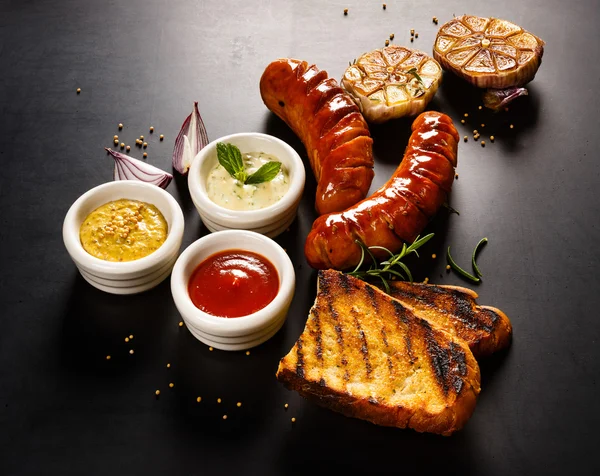 Grillad korv med tillägg olika typer av dips på svart bakgrund — Stockfoto