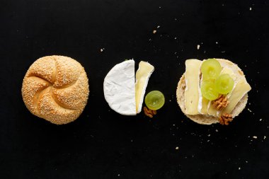 Camembert peyniri, üzüm ve siyah bir zemin üzerine ceviz ile sandviç