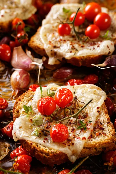 Tostadas con queso derretido, tomates cherry y hierbas aromáticas — Foto de Stock