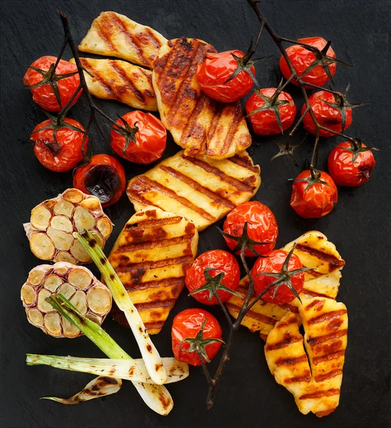 Legumes grelhados com queijo halloumi em um fundo preto — Fotografia de Stock