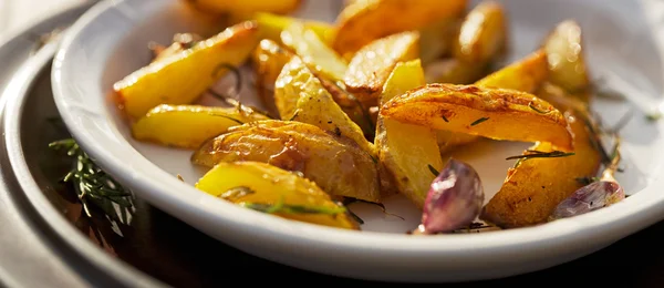 Geroosterde aardappel partjes met toevoeging rozemarijn en knoflook — Stockfoto