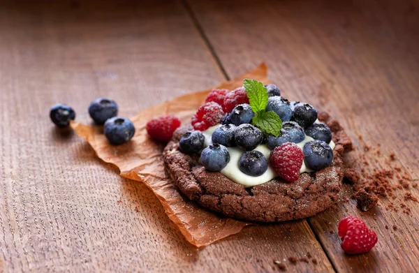 Pastel de chocolate con crema de vainilla y bayas frescas — Foto de Stock